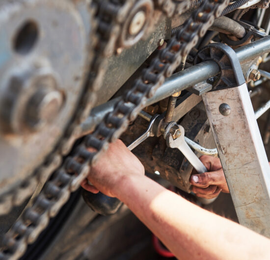 Combine machine service, mechanic repairing motor outdoors.